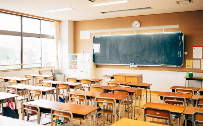 Empty classroom with chalkboard and desks.